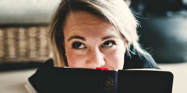Woman who is smart hides behind a book after mispronouncing simple phrases