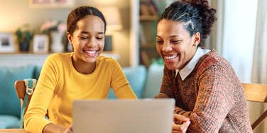 mom helping teen daughter on laptop