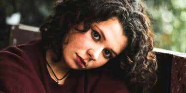 Person sitting outdoors and looking at the camera.