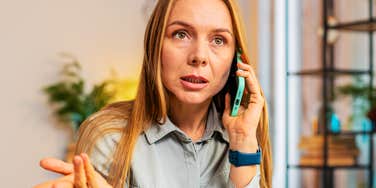 Woman talking on a phone indoors, gesturing with her hand.