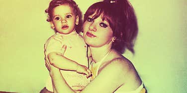 A woman holding a baby indoors.