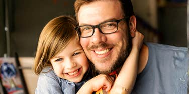 A man smiling while holding a young child.