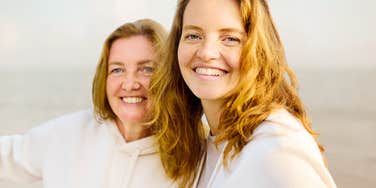 Mother who stayed close to her adult daughter laughing at the beach