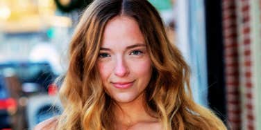 Person with long hair looking at the camera outdoors.