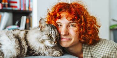 Woman who loves her cat cuddling it on a couch 