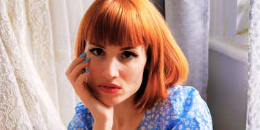 Person resting their face on their hand indoors.