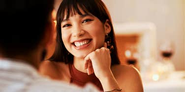 person smiling at someone across a table in a softly lit indoor setting