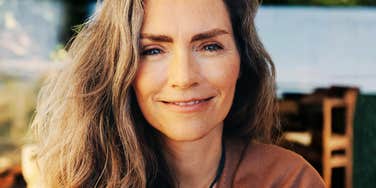 close-up portrait of a confident woman in her fifties with natural lines and soft smile.