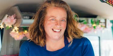 Young woman sitting on a park bench, resting her face in her hands with a pensive, melancholic expression, appearing lost in thought.