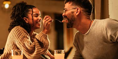 Playful couple enjoying dinner together, highlighting romantic habits noticed by wives, according to a clinical psychologist”