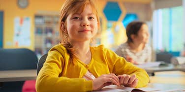 little girl sitting in the classroom at school learning