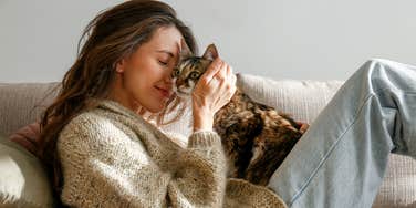 woman snuggling purring cat on lap