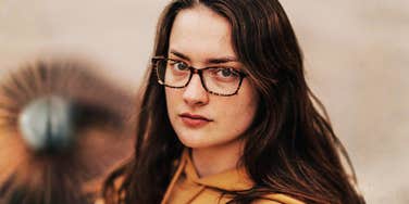 A woman in glasses looking directly at the camera.