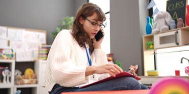 teacher talking on phone while sitting in classroom
