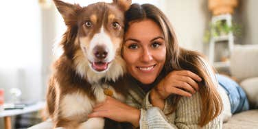 woman laying next to her Australian Shepherd dog