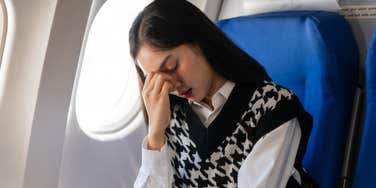 woman annoyed sitting in plane seat