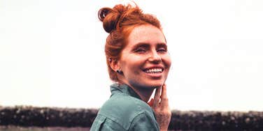 Happy red-headed woman smiling, illustrating the difference between fleeting good days and lasting happiness
