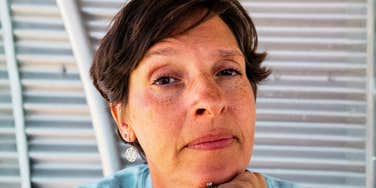 Middle aged woman leaning forward on hand.