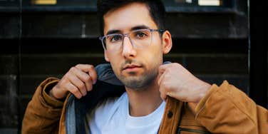 serious young man adjusting jacket, intense direct gaze