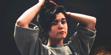 Woman fixing her hair looking confused.