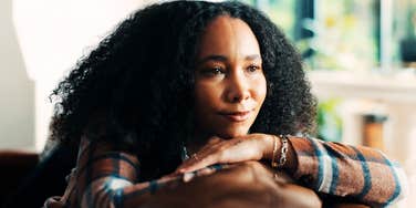 Kind, sensitive woman resting her head on her hands on the back of a couch, reflecting vulnerability that narcissists may target