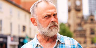 A man frowning and looking skeptical into the camera, illustrating the frustration and confusion of a Baby Boomer navigating changing generational norms.