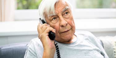 An annoyed Baby Boomer parent holding a vintage landline phone, illustrating common habits and communication barriers that can cause tension with adult children.