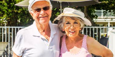 A happy senior couple laughing on a beach vacation, representing the hard-earned, authentic wisdom about love shared by Baby Boomers who have been together for decades.