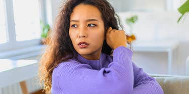 annoyed serious woman sitting in living room with bright overhead lights