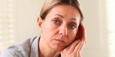 A professional woman sitting at a desk with a weary expression, illustrating the emotional toll of staying in a role one has outgrown and the need for career growth.