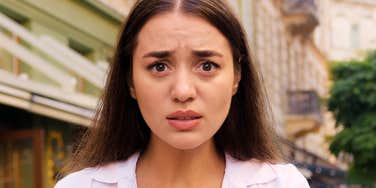 An upset woman with arms crossed, illustrating the 'emotional reactivity' and rigid expectations that can characterize the 'difficult' partner in a relationship.