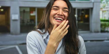Woman laughing and covering mouth after using commonly misspelled phrase
