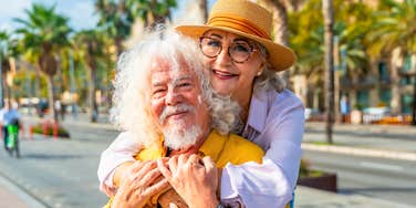 Couple in their seventies embracing each other at home, illustrating the qualities shared by couples who still reach for each other later in life