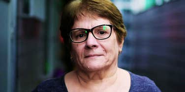 End-Of-Life Nurse Says These Regrets Hit People All At Once At The Very End A serious senior end-of-life nursen in a hallway, capturing the 'moment of reckoning' and the spiritual or emotional clarity that often occurs in the final stages of life.