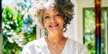 A happy sixty-year-old woman smiling in natural light outdoors, illustrating the 'internal peace' and emotional maturity that experts say sustains long-term marriages.