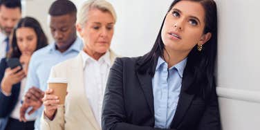 uncomfortable woman waiting in line with people standing too close to her