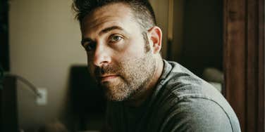 A man with a beard looking distant and lost, illustrating the 'flat affect' and signs of high-functioning depression that go beyond temporary sadness.