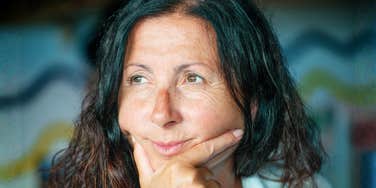 A portrait of a mature woman with a pensive and relaxed expression, representing the 'second adulthood' shift toward letting go of societal expectations.