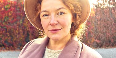 A thoughtful forty-year-old woman walking in an autumn setting, illustrating the quiet transition from feeling 'wrong' to understanding the true nature of loneliness.