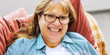 Midlife woman in casual clothes lying on a couch and smiling thoughtfully, illustrating Gen X quotes that resonate more deeply in midlife