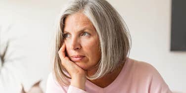 A woman resting her head in her hand while looking out a window, capturing the quiet, reflective moments of navigating life's complex emotional transitions.
