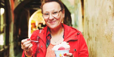 A smiling mature woman eating a cold treat on a sunny day, representing the everyday lifestyle habits that a new study suggests could impact brain health by up to forty-two percent.
