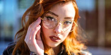 high-iq woman touching her glasses looking interested