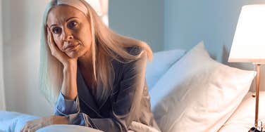 tired high iq woman refusing to go to sleep sitting up in bed