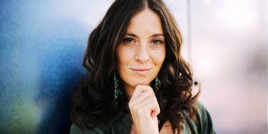 A candid portrait of a stylish urban female looking at the camera with a self-assured smile, illustrating the 'X-factor' hiring managers look for beyond a resume.