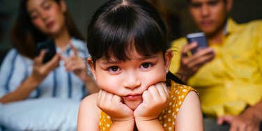 little girl feeling like an outsider in her own family being ignored by parents