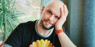 A middle-aged man sitting by a window appearing pensive, illustrating the common adult struggles of former "gifted kids," such as perfectionism, burnout, and the pressure to perform.