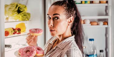 A woman craving sweets in her kitchen at night, capturing the common struggle of balancing nighttime hunger with long-term health goals after 50.