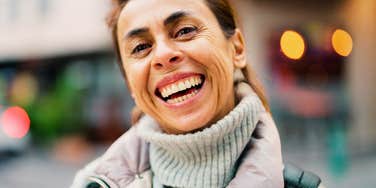 Confident middle-aged Hispanic woman smiling while standing on a city street, illustrating the life lessons learned in your twenties that make your fifties feel easier