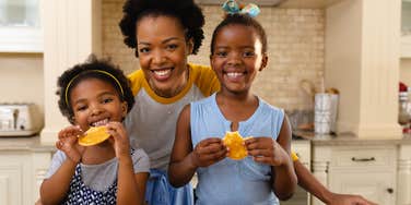 mom smiling with two daughters in kitchen at home